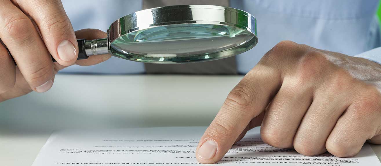 Businessperson inspects a document with a magnifying glass
