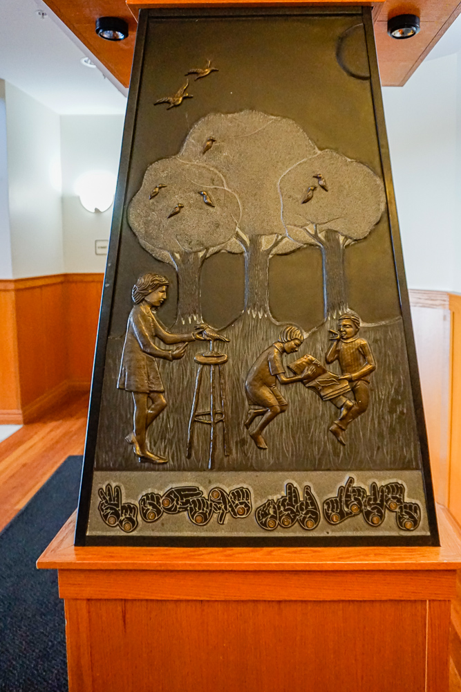 Tactile sculpture with finger signs and braille that says 'we shape our lives'